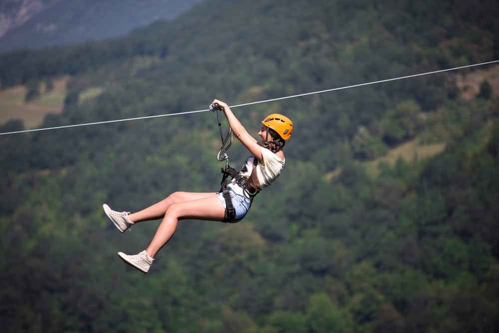 A woman riding a zipline in the mountains.