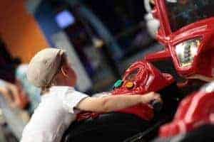 A young boy playing a motorcycle game at an arcade.