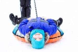 Small child upside down on tube in the snow