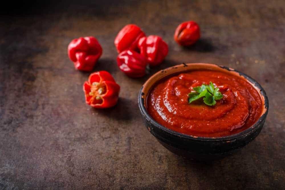 A bowl of hot sauce with chili peppers.