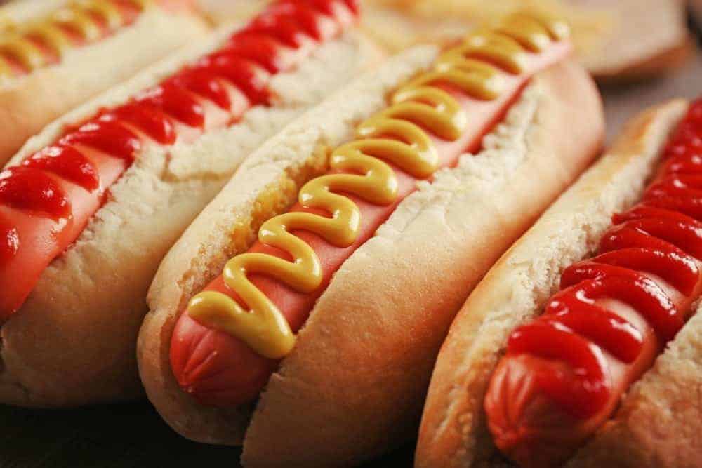 A row of hot dogs with mustard and ketchup.