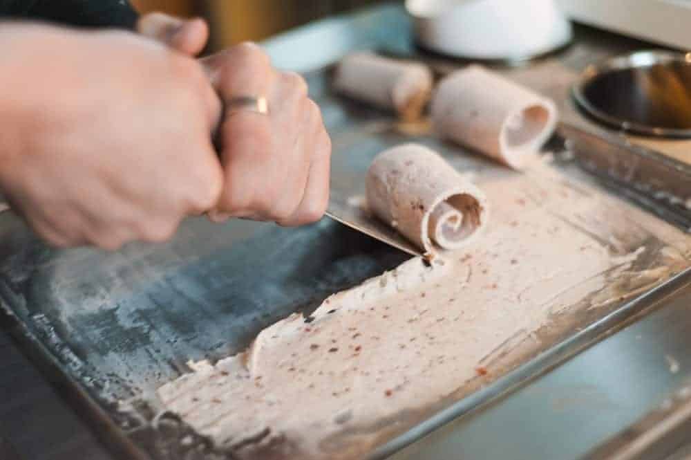 A woman making rolled ice cream.