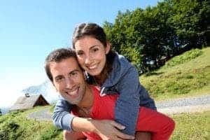 Happy couple posing for a photo near their cabin in the mountains.