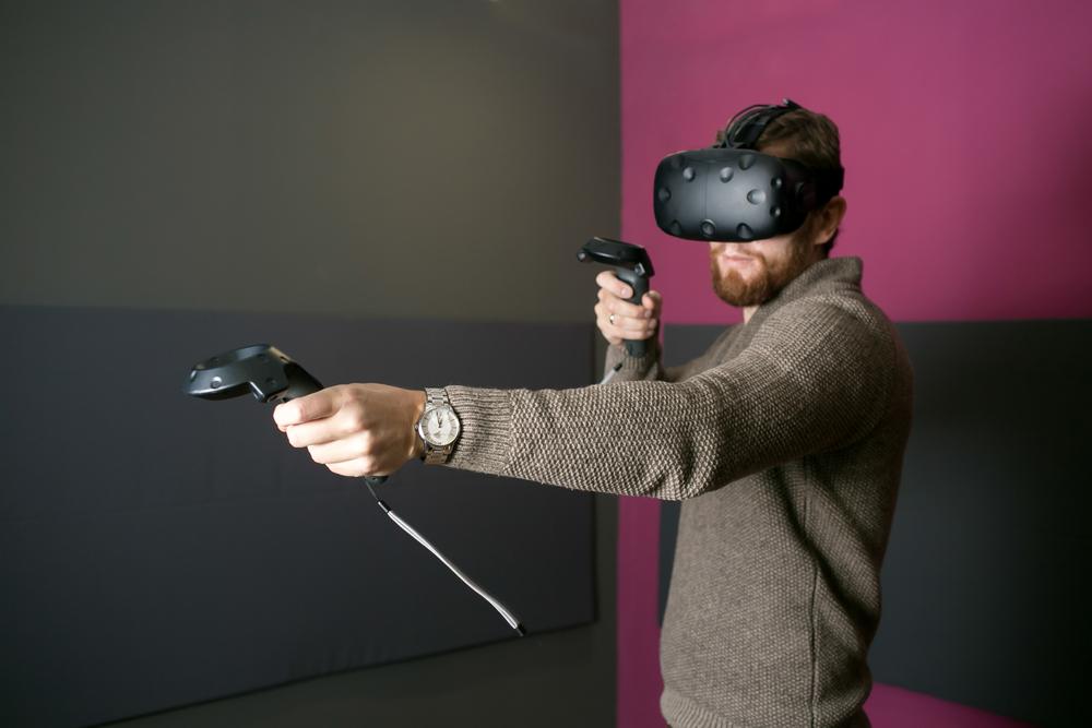 A man wearing a virtual reality headset and holding two joysticks.