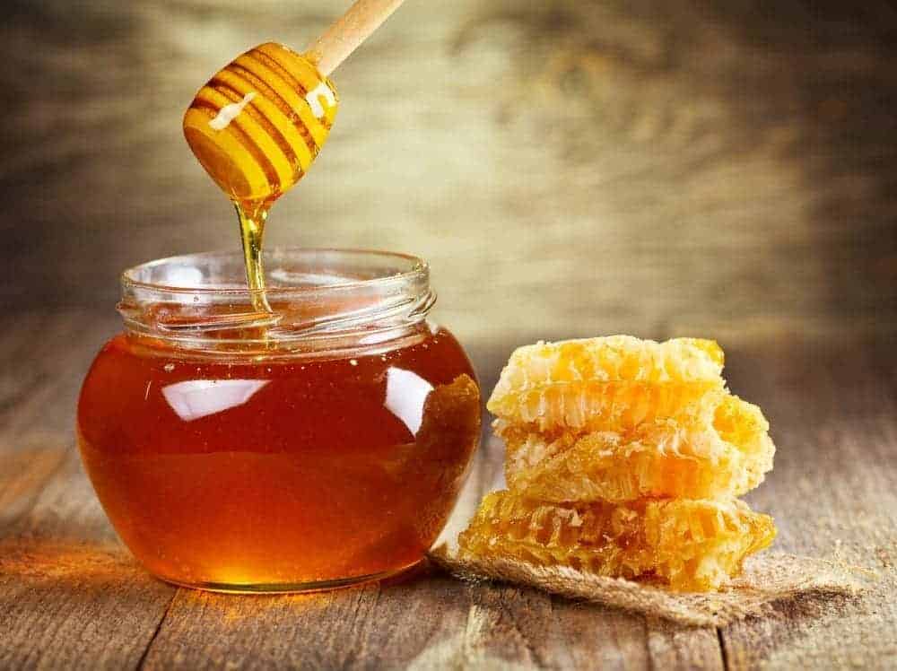 A jar of honey, a honey dipper, and honeycomb.