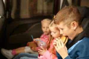 Kids eating in the back of a car.