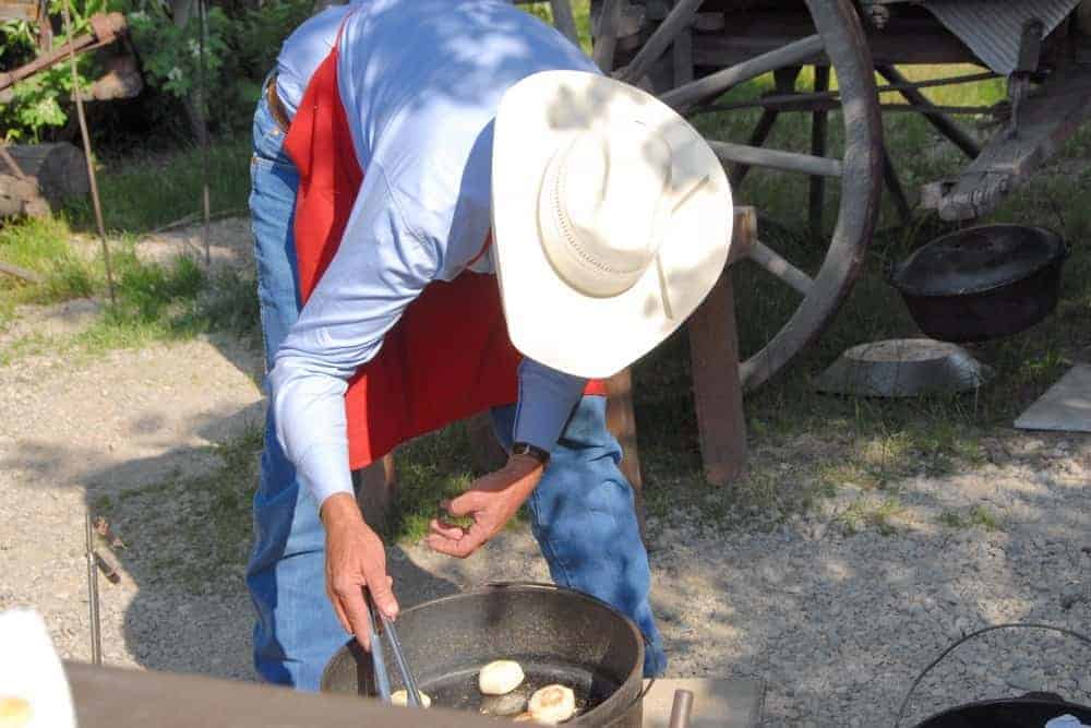 A cowboy cooking outdoors.