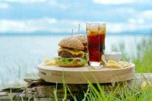 Two cheeseburgers with a lake in the background.