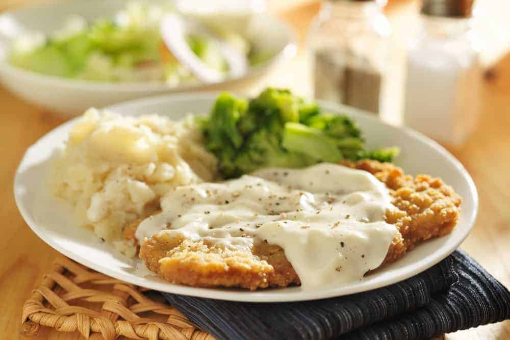 Chicken fried steak with peppered gravy and side dishes.