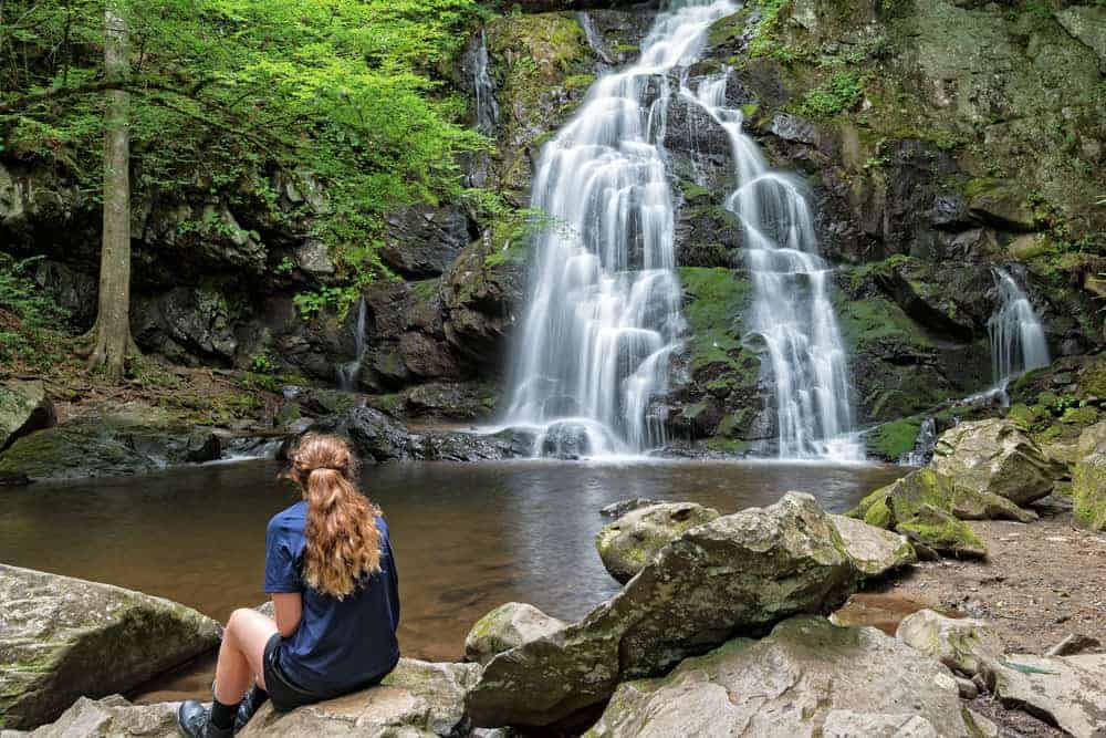 girl sitting in front of waterfall
