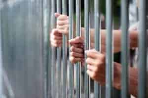 hands behind bars in jail cell