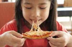 girl eating slice of pizza