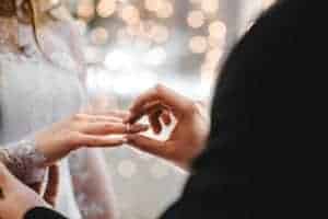 man putting ring on woman's finger at wedding