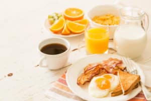 coffee, orange juice, milk, oranges, eggs, toast, bacon