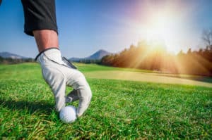 man with golf glove putting ball on green