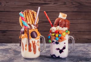 two gourmet milkshakes with cookies and candy toppings