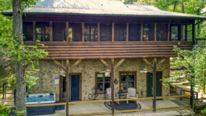 A large screened in porch with plenty of seating and a lower patio with hot tub