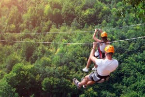 two friends ziplining through the trees