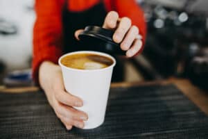 barista handing cup of coffee to go