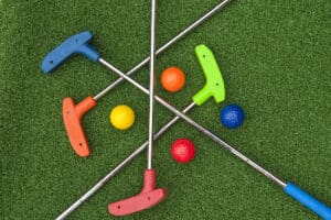 four mini golf putters and balls