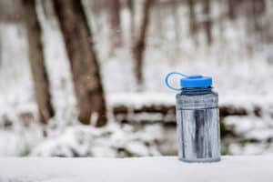water bottle sitting on snow-covered log