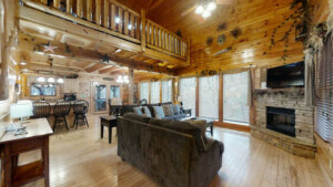 Log cabin with loft game room showing living room with 2 charcoal couches, black coffee table and 2 end tables, a electric fireplace and smart tv with cable