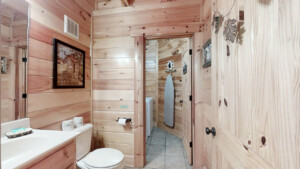 Half bathroom on main level with laundry room attached with full size washer and dryer, iron and ironing board