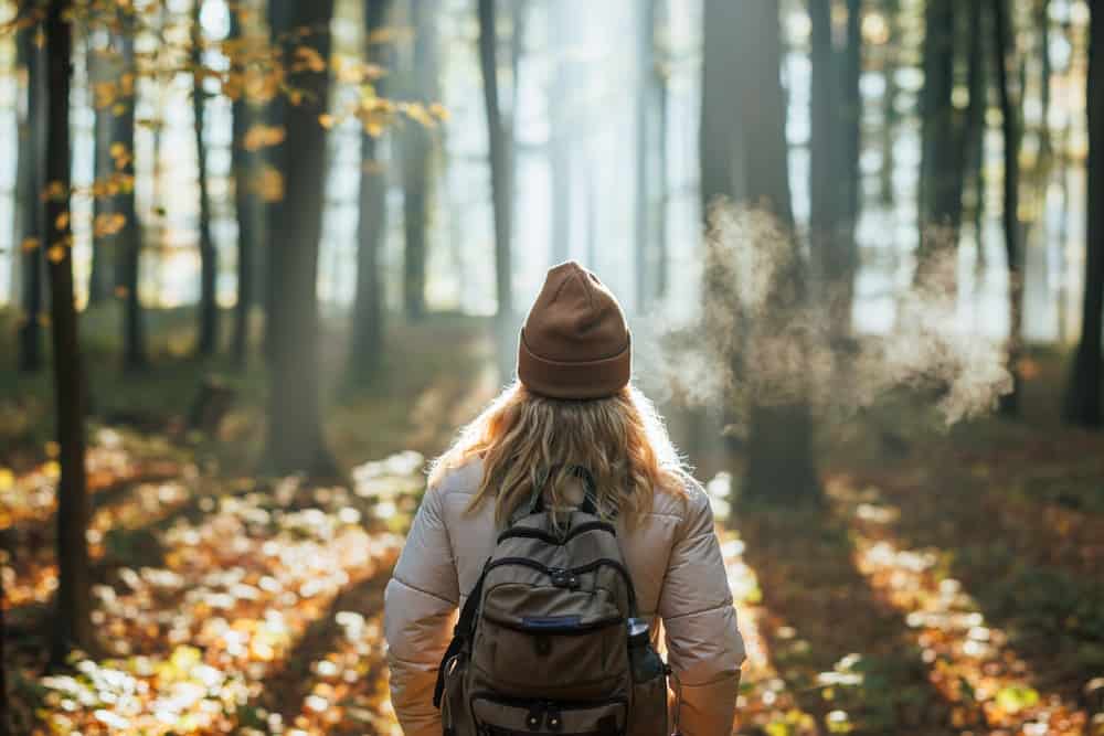 back of female hiker wearing winter gear and backpack